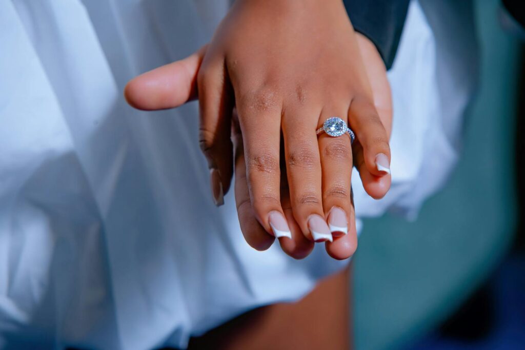 Close-up photo of hands with engagement ring, symbolizing love and commitment.