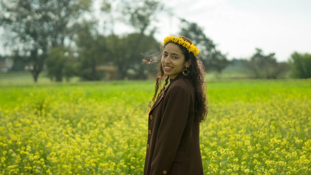 A smiling woman wearing a floral crown in a lush green field in Morocco.
