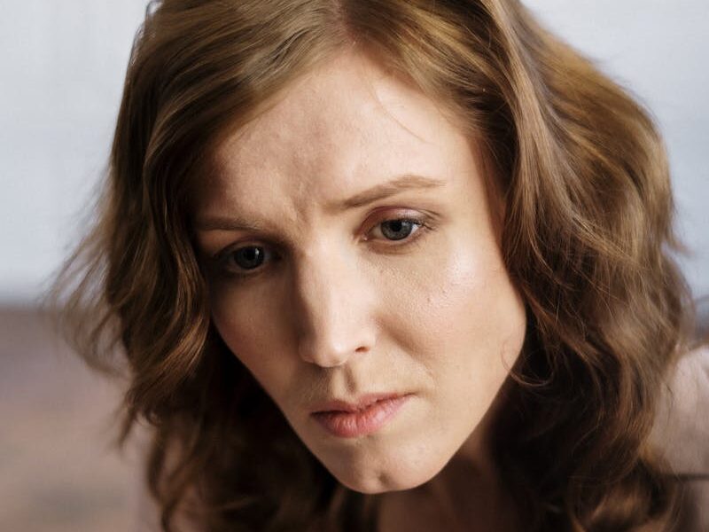 A woman with curly hair in deep thought, indoors, conveying emotion.