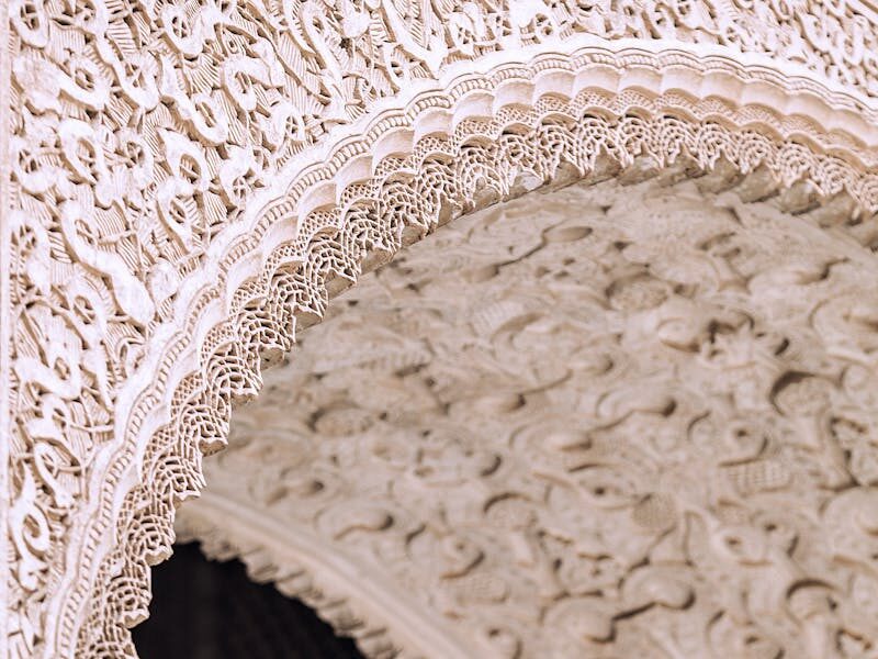 From below of aged stone building with decorative arch in form of lace in city
