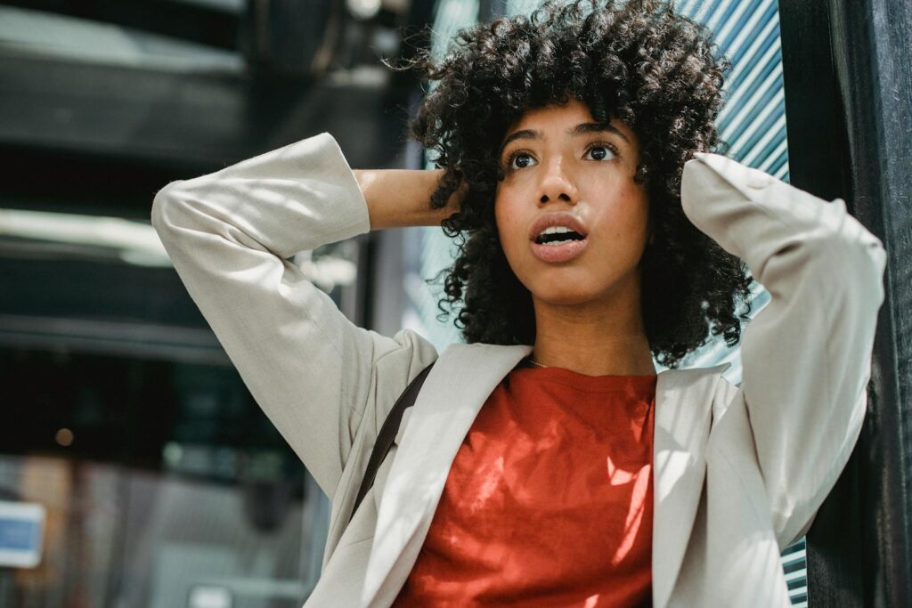 Portrait of a surprised young woman with curly hair in an urban setting.