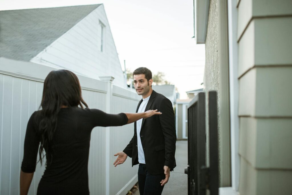 Man and woman having an argument in a suburban alleyway during the day.