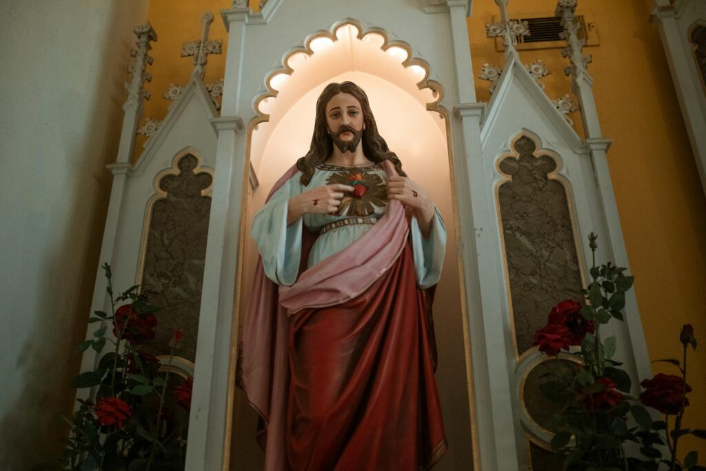A religious statue of the Sacred Heart of Jesus within a church setting, symbolizing faith and devotion.