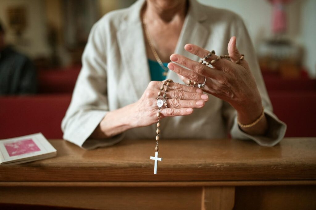 Close-up of a woman praying with a rosary in a church environment, symbolizing faith and spirituality.