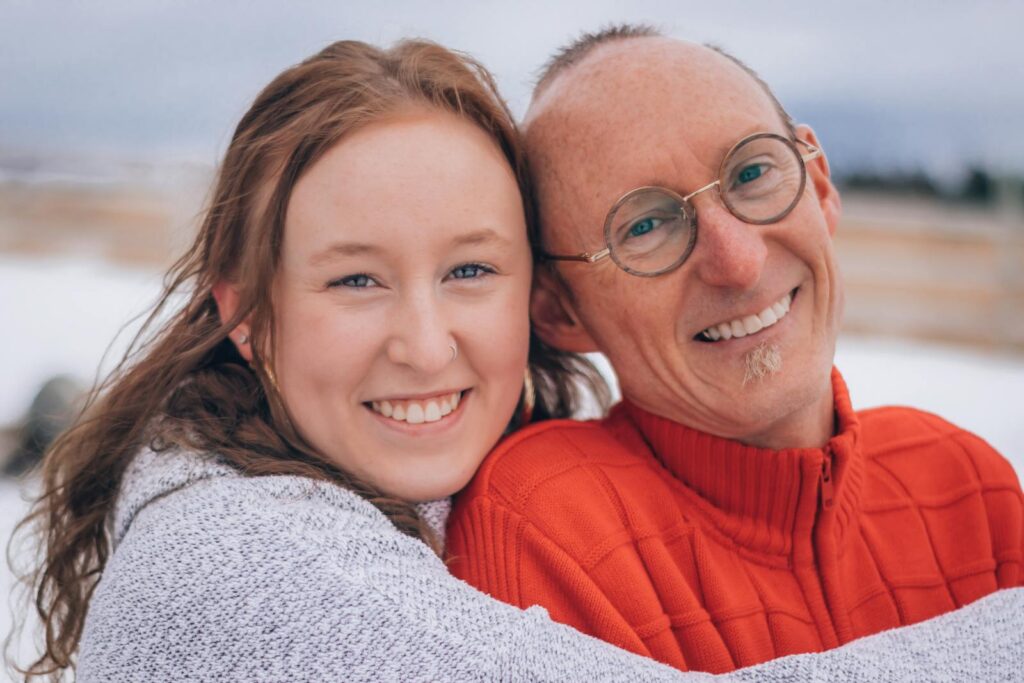 Smiling friends embracing warmly in a snowy setting, showcasing friendship and happiness.