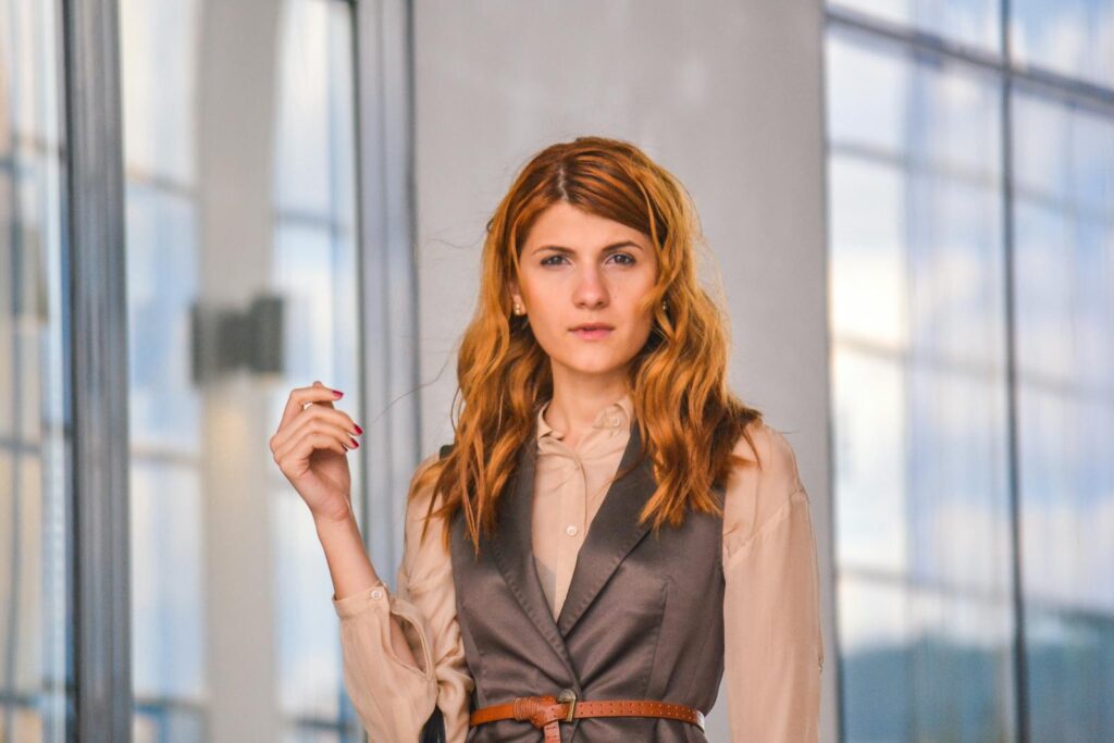 Confident woman posing stylishly indoors with modern architecture.
