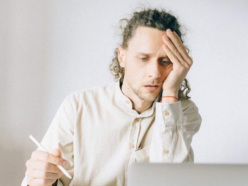 Young man overwhelmed by work at his desk, showing stress and fatigue.