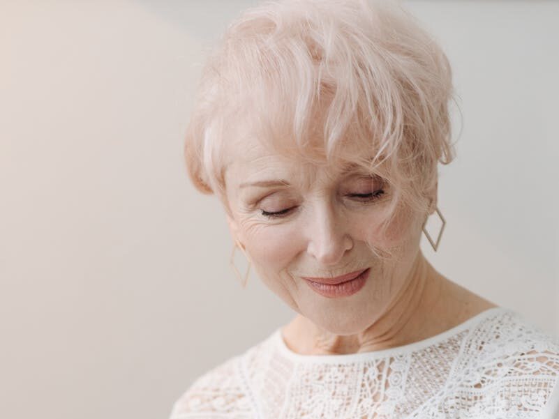 Elegant senior woman with white hair reading a magazine, captures grace and relaxation.