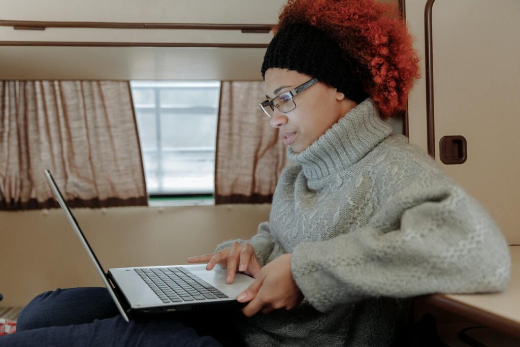 A Woman in a Knitted Sweater Using a Laptop