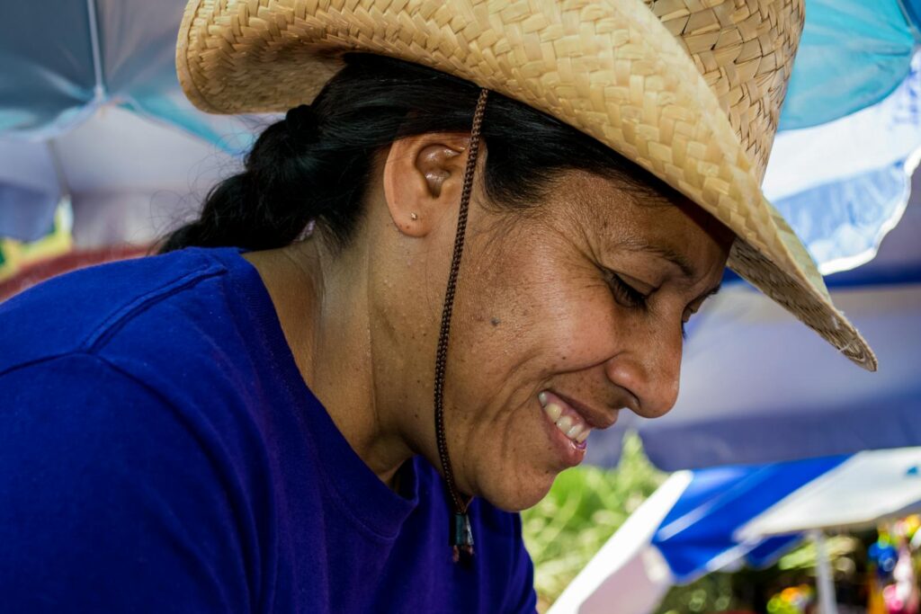 A cheerful woman in a straw hat enjoying a sunny day at Los Algodones market in Mexico.
