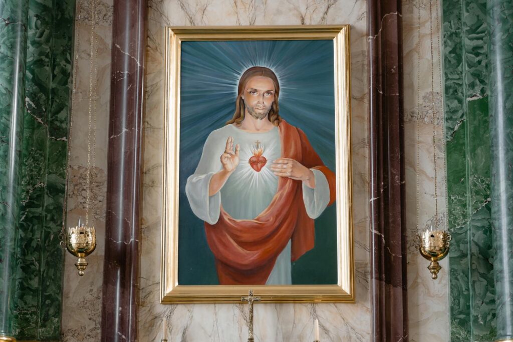 A detailed painting of the Sacred Heart of Jesus displayed indoors with ornate decor.