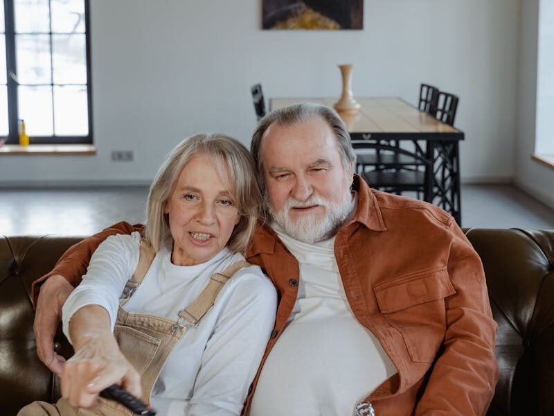 Smiling senior couple relaxing with popcorn during a cozy movie night at home.
