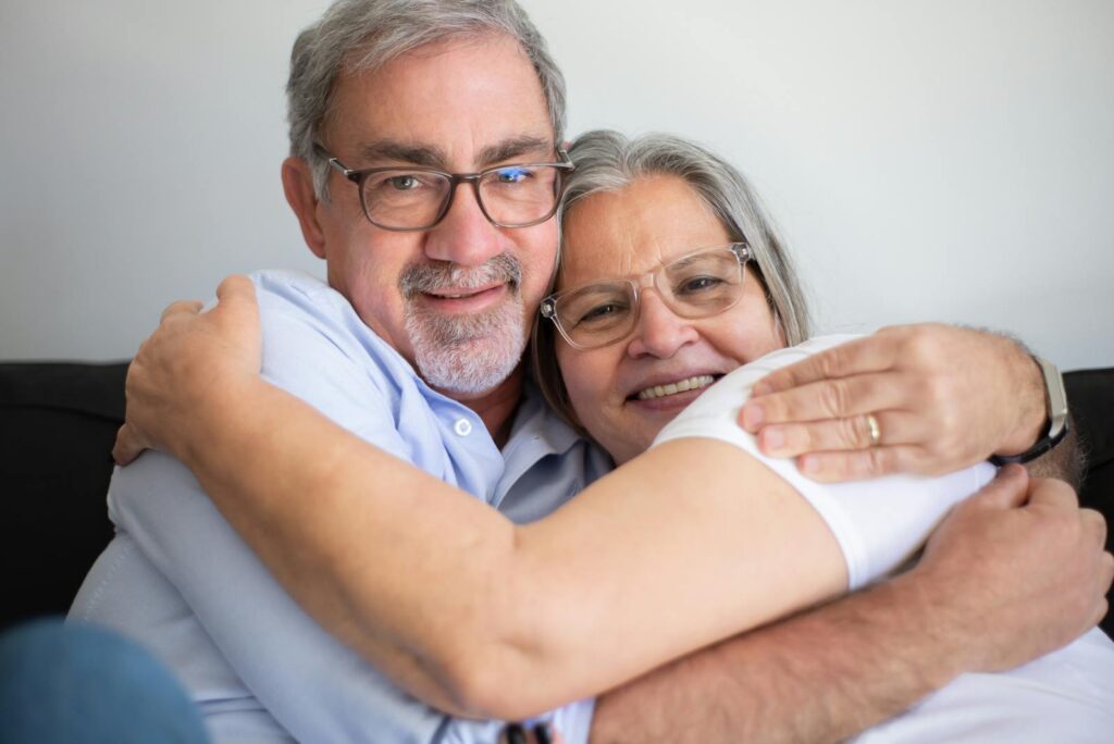 Happy elderly couple embracing indoors, symbolizing love and companionship.
