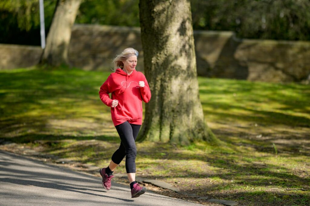 Elderly woman enjoying a healthy outdoor jog in a sunlit park.