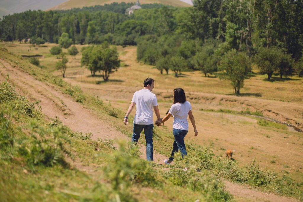 Couple walking hand in hand through a lush landscape in Gəncə, capturing a tranquil moment in nature.