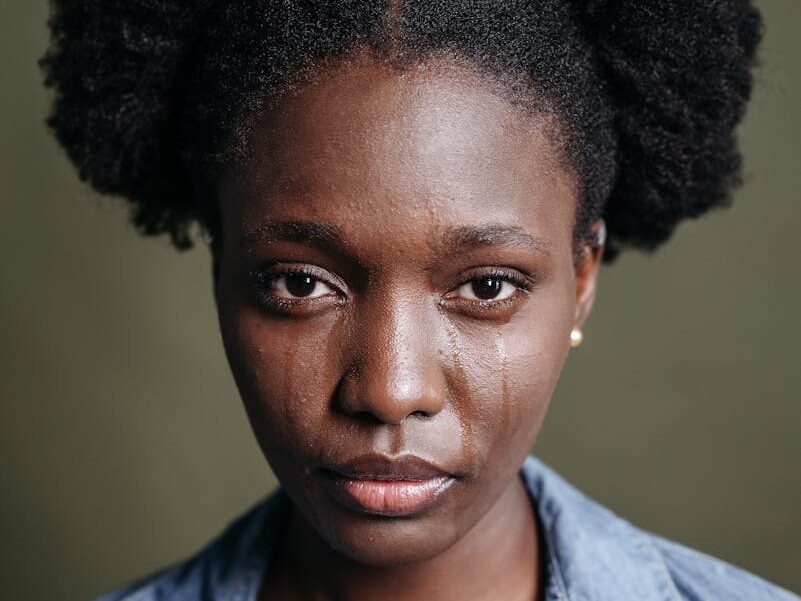 Close-up portrait of a woman with tears on her face, conveying emotion.