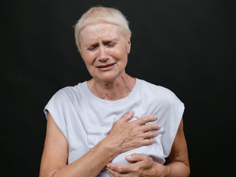 Elderly woman showing intense emotion against a dark background in a studio setting.