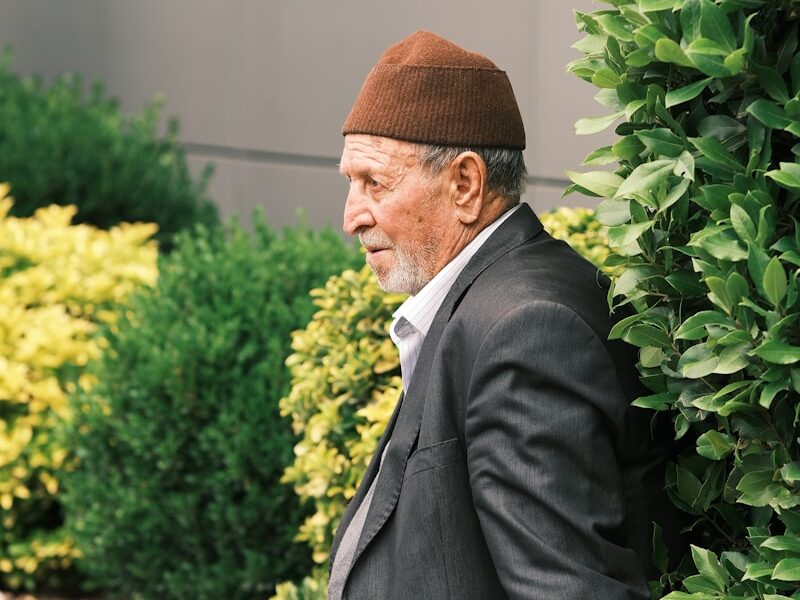 A man in a suit and hat sitting on a bench