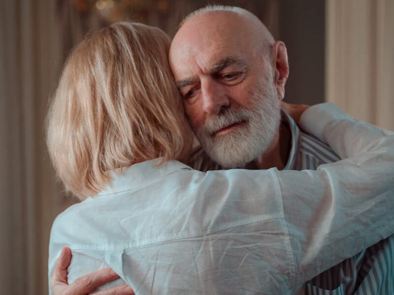An elderly couple shares a warm embrace, symbolizing love and companionship.