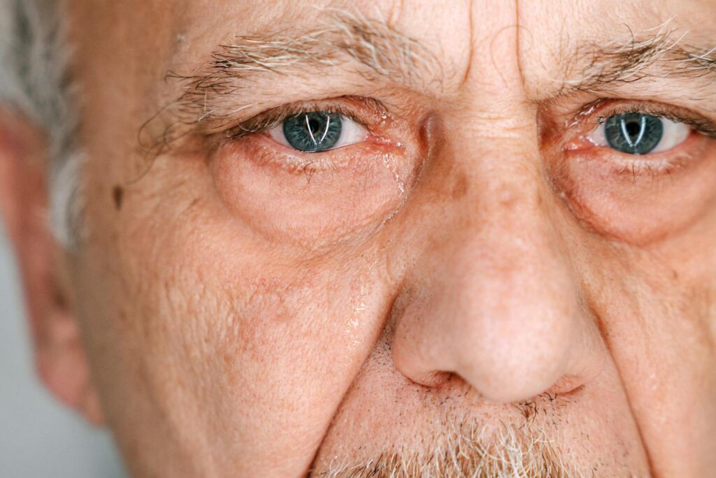 Close-up of an elderly man's face expressing deep emotion and tears.