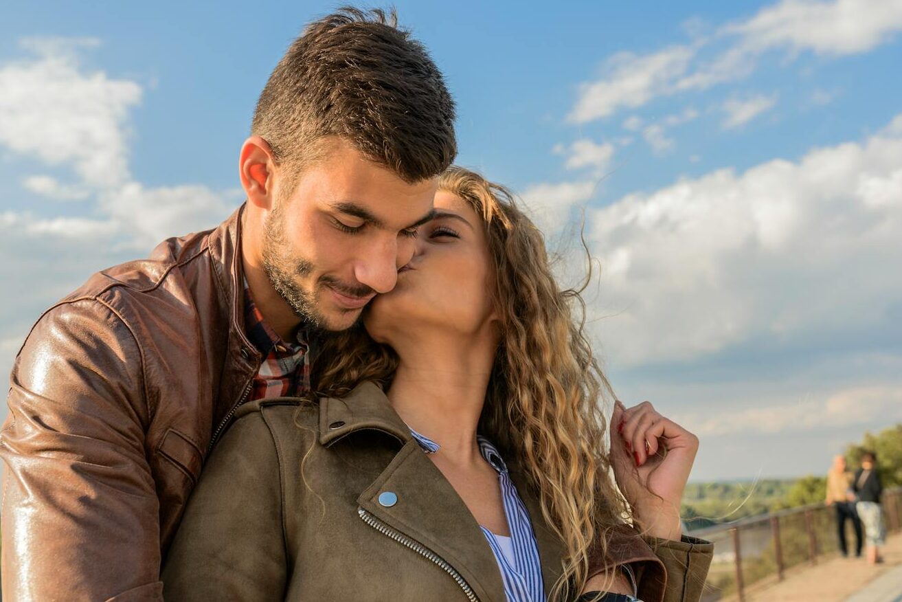 A loving couple embraces under a clear sky, showcasing romance and togetherness.
