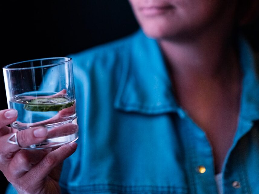 a woman wearing glasses holding a glass of water