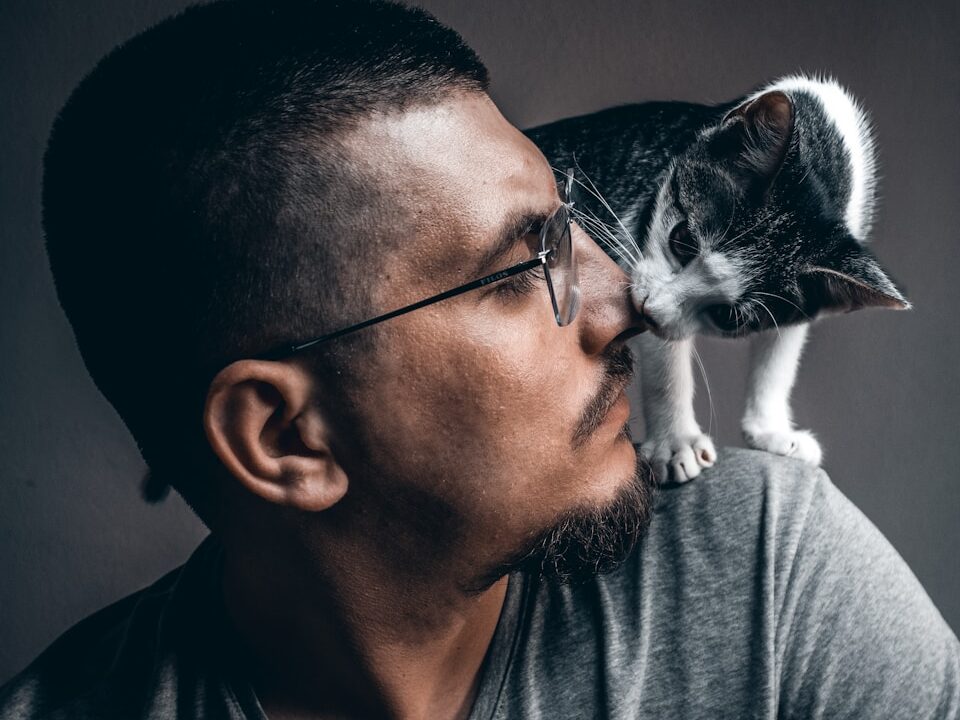 man in gray crew neck shirt holding white and black cat