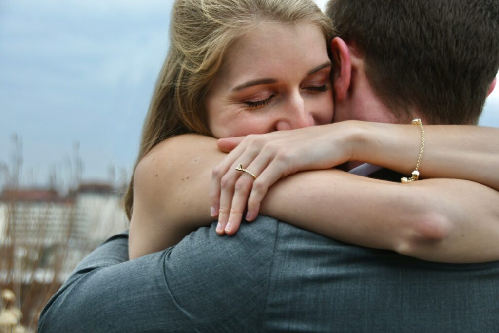 man in blue denim jeans kissing woman in white shirt