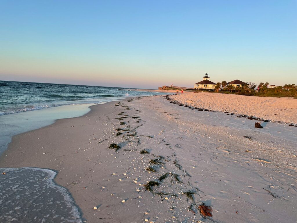 a sandy beach with a light house in the distance