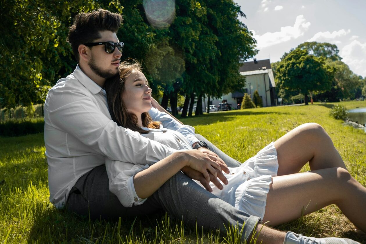 man and woman sitting on green grass field during daytime