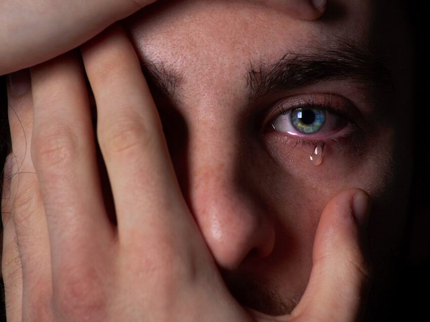 a close up of a person covering their face with their hands