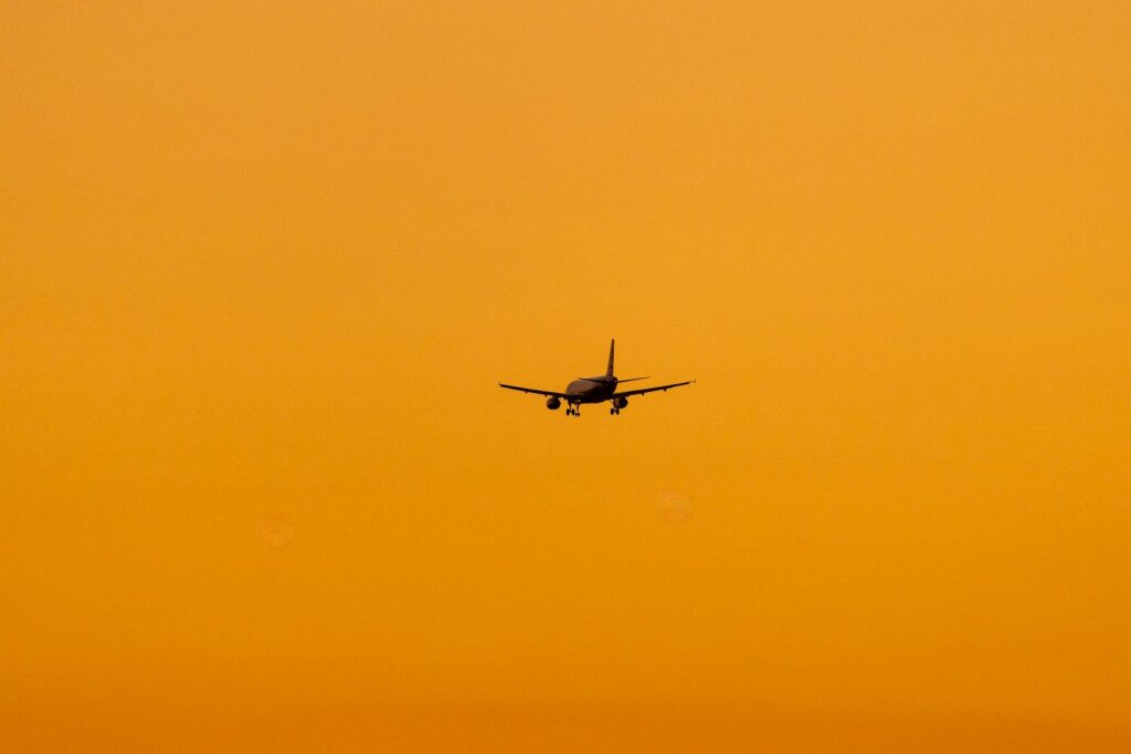 An airplane is flying in the sky at sunset