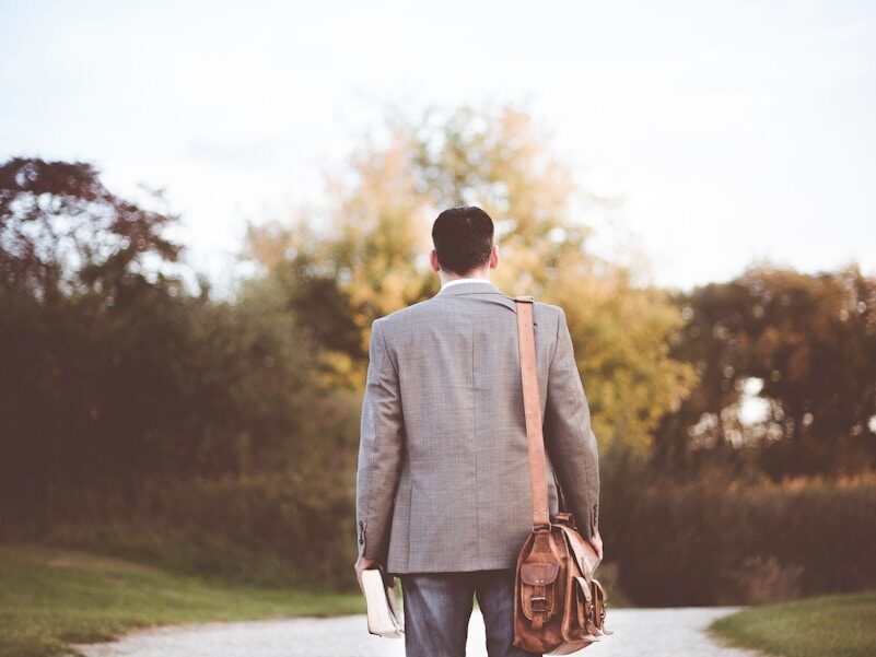 man wearing gray coat standing near road during daytime