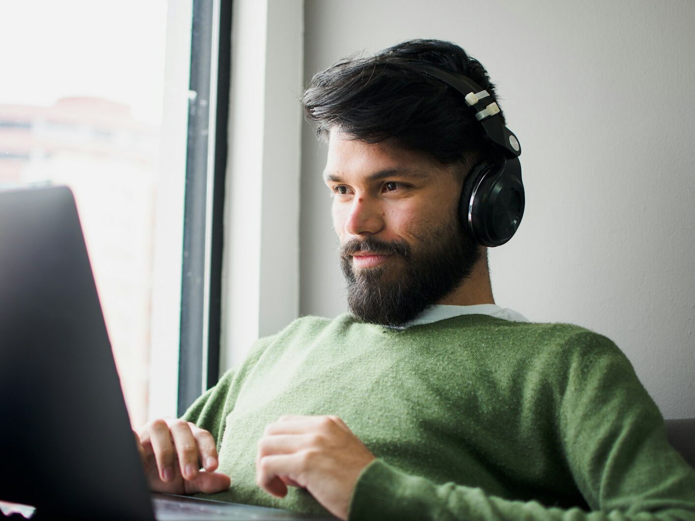man wearing headphones while looking at MacBook