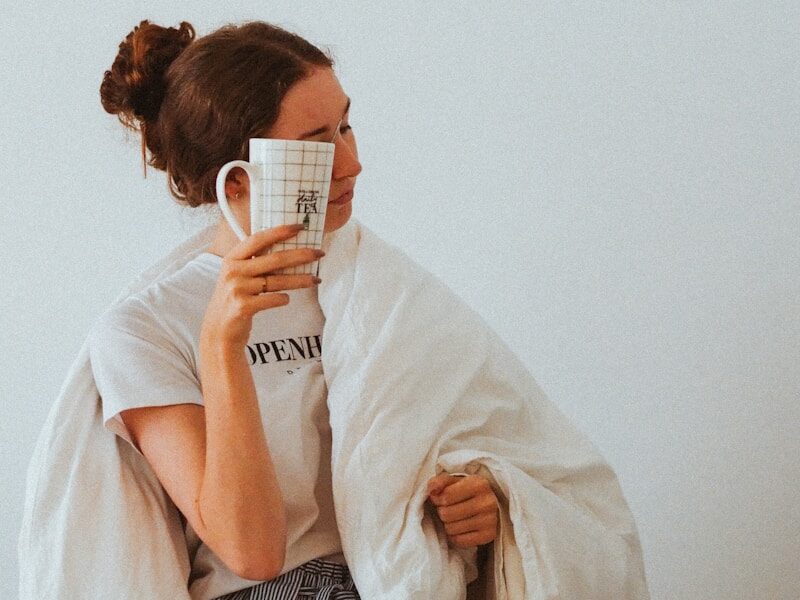 woman in white robe holding white ceramic mug