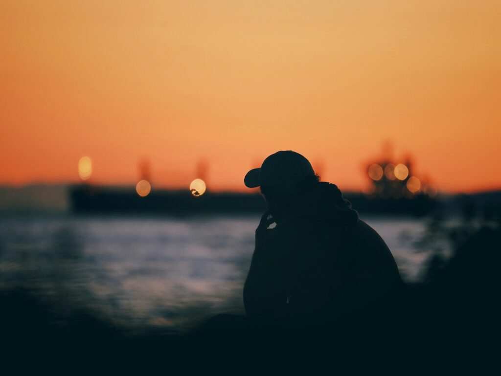 A silhouette of a person standing in front of a body of water