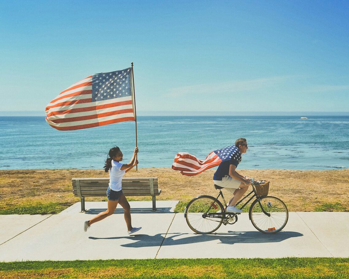 man riding bike and woman running holding flag of USA