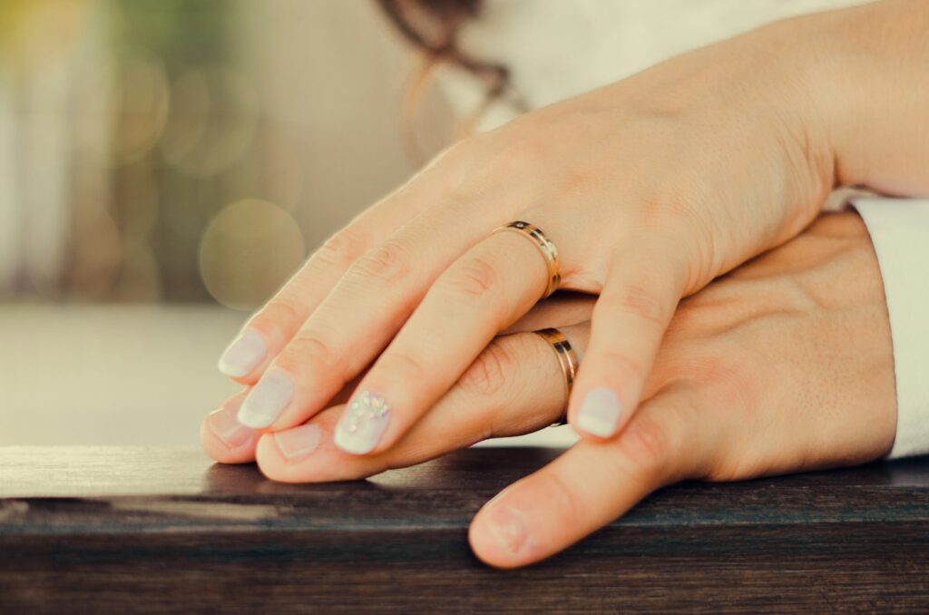 person wearing gold ring on brown wooden table
