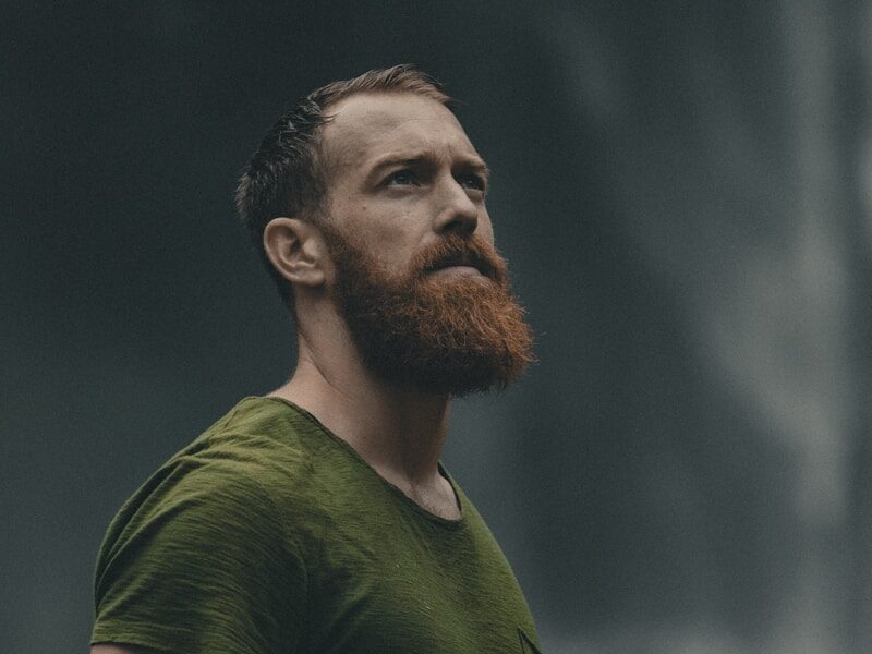 man wearing green crew-neck t-shirt looking upwards