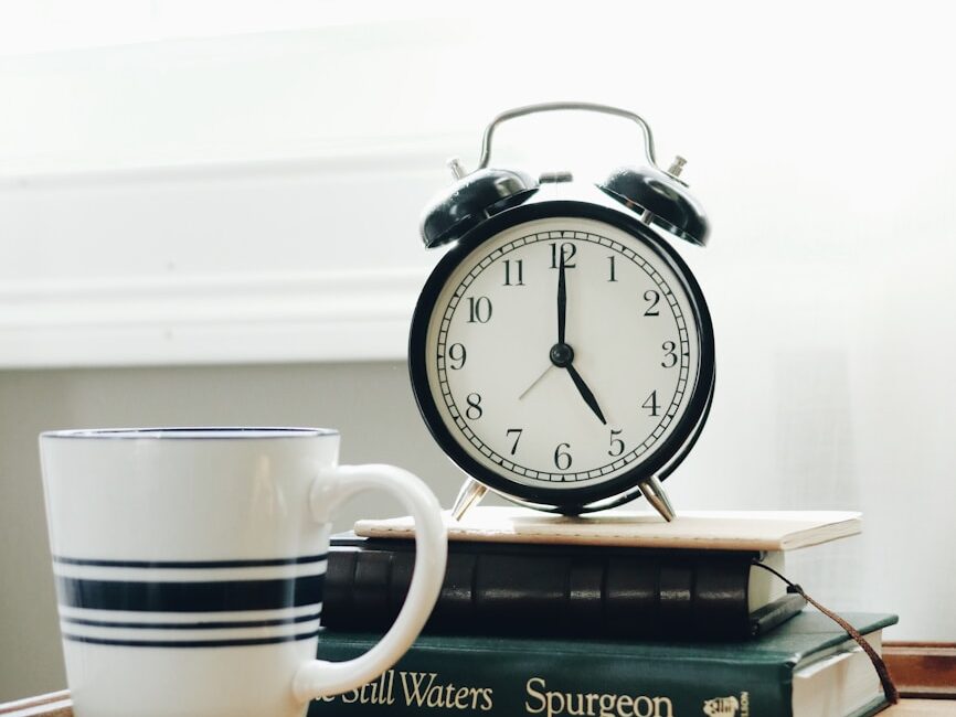 white ceramic mug beside white and black analog alarm clock
