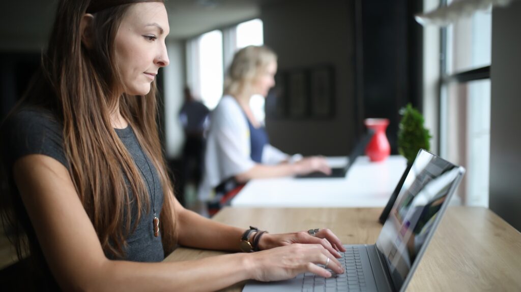 woman in white tank top using laptop computer
