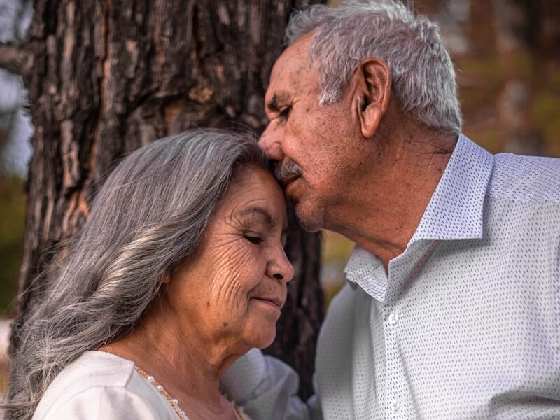 man in white button up shirt kissing woman in white sleeveless dress