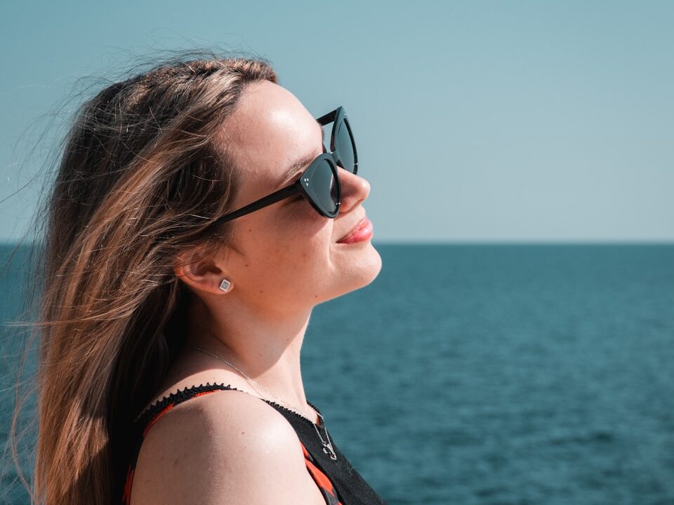 a woman wearing sunglasses looking out over the water