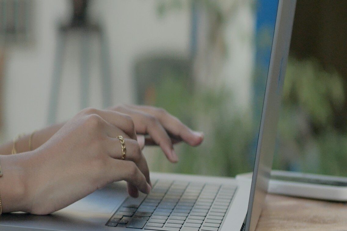 a woman using a laptop computer on a wooden table