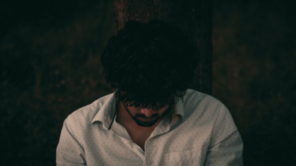 a man in a white shirt is looking down