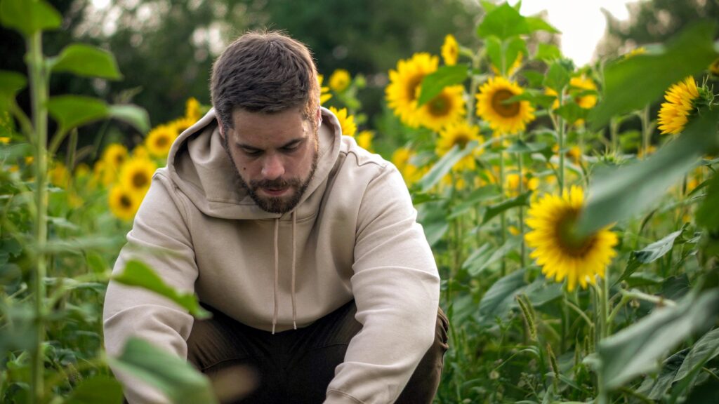 man in white hoodie sitting on green grass field