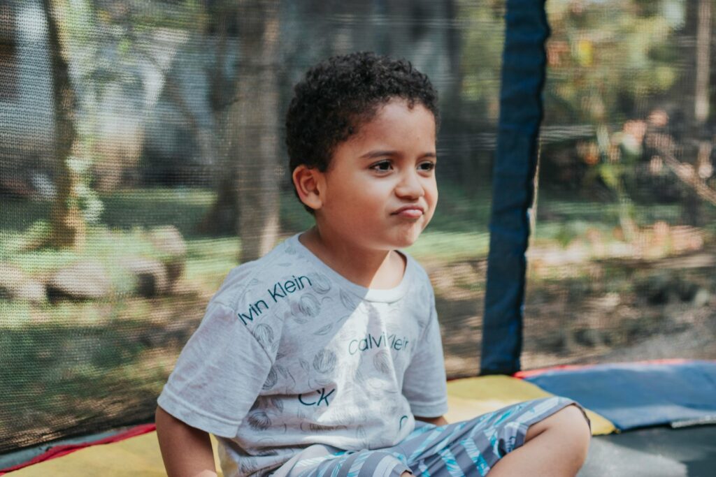 a young boy sitting on top of a trampoline