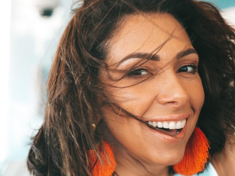 a woman with orange earrings smiling at the camera