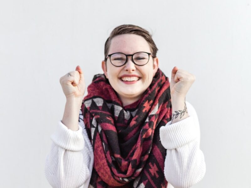 woman in white sweater wearing red scarf and black framed eyeglasses