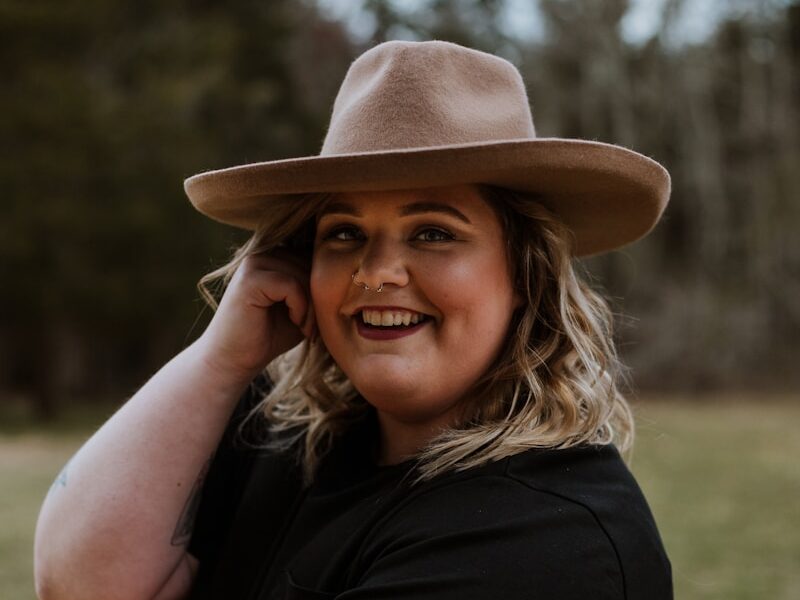 woman in black sleeveless dress wearing brown fedora hat